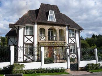 Пример красивой отделки фасада дома белого цвета в фахверка стиле