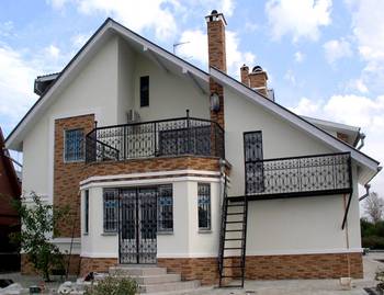 Облицовка фасада дома в авторского стиле с ковкой