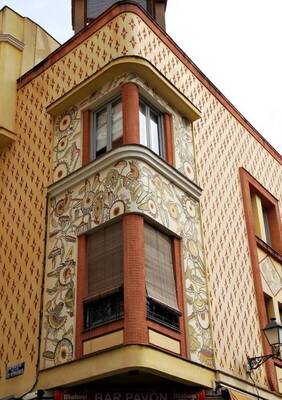 Отделка фасада дома бежевого цвета с интересными окнами