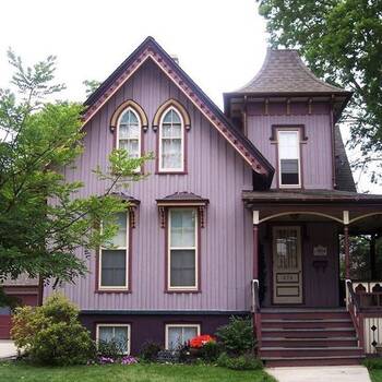 Внешняя отделка загородного дома фиолетового цвета с интересными окнами
